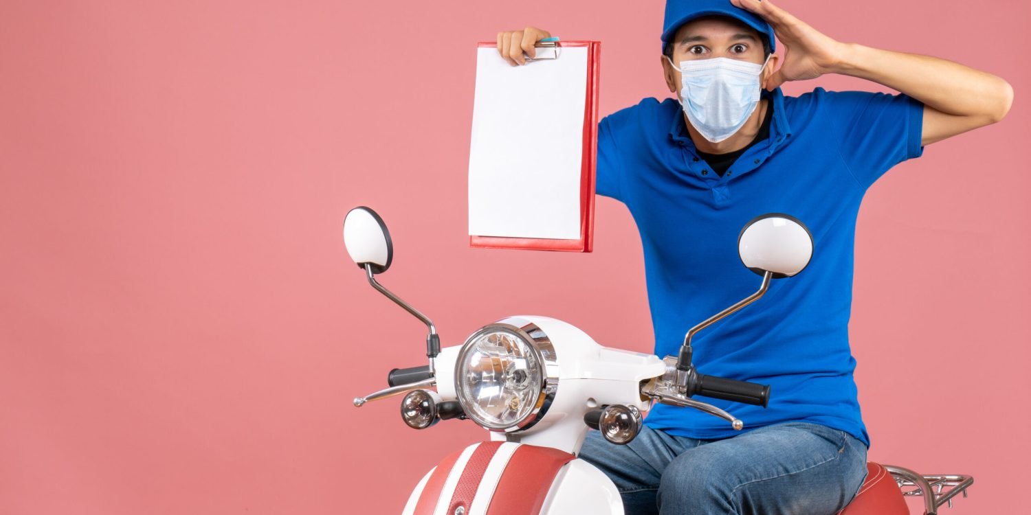 vue-de-dessus-d-un-livreur-choque-en-masque-portant-un-chapeau-assis-sur-un-scooter-montrant-un-document-sur-une-peche-pastel
